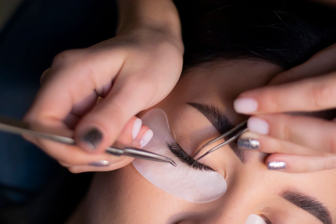 Clienta recostada con antifaz durante la aplicación de extensiones